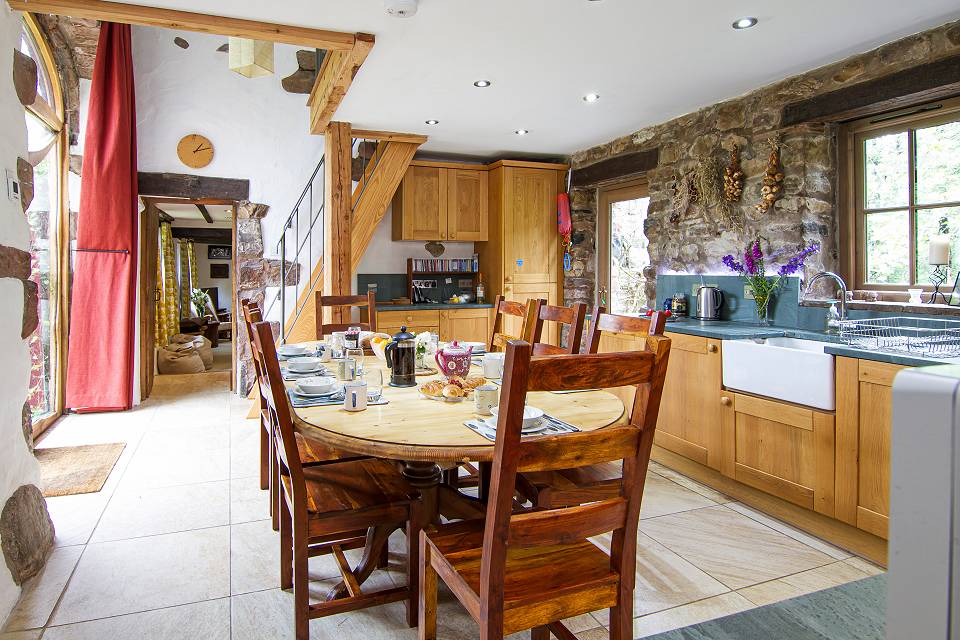 kitchen table laid for breakfast with traditional wooden chairs, cupboard doors and sink