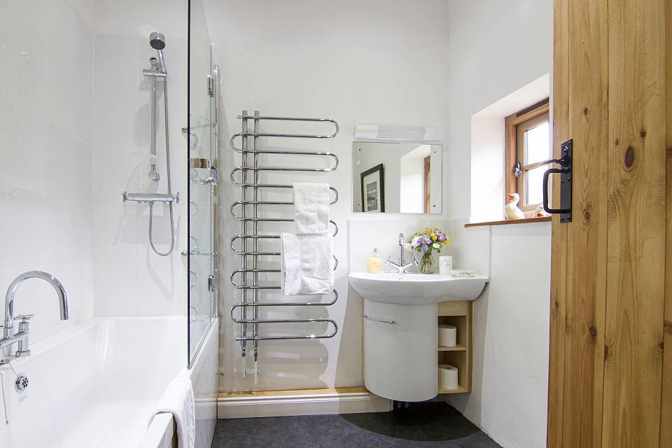 Modern bathroom with bath and shower over, heated towel rail and sink